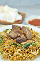 Indonesian style stir fry noodles with beef, egg,  green mustard, and crackers.