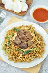 Indonesian style stir fry noodles with beef, egg,  green mustard, and crackers.