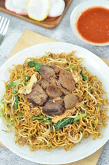 Indonesian style stir fry noodles with beef, egg,  green mustard, and crackers.