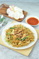 Indonesian style stir fry noodles with chicken, egg,  green mustard, and crackers.