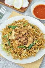 Indonesian style stir fry noodles with chicken, egg,  green mustard, and crackers.
