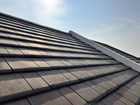 Tiled roof of a house under the bright sun, showcasing modern residential architecture details