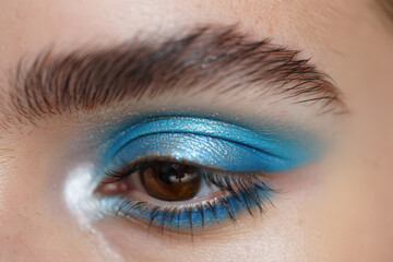 Fototapeta premium Close Up of a Woman's Eye with Shimmering Blue Eyeshadow and Defined Lashes Highlighting Beauty and Cosmetic Artistry in a Studio Setting for Editorial Purposes