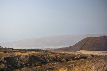 Fototapeta premium March 25 2025 Brown Hill in Vast Open Landscape with Mountains in the Distance, Japan