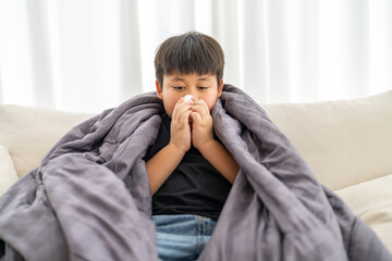Young asian boy sneezing or blowing his nose and mouth with tissue, cold allergies or illness, health, virus and flu season, RSV, Influenza, childcare and hygiene practices, especially for children
