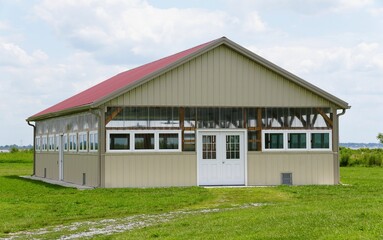 Obraz premium A light beige event building, nestled in a grassy field, under a vibrant red roof, perfect for gatherings near Fort Delaware, U.S.A