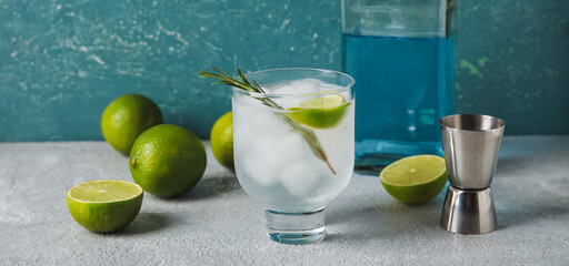 Glass of cold gin tonic on color background