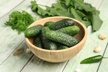Bowl with fresh cucumbers for preservation on light wooden background