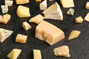 Pieces of tasty cheese on dark background