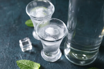 Bottle and glasses of vodka on black background