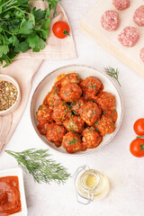 Bowl of tasty meat balls with sauce on light background