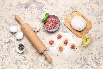 Raw dough with minced meat and ingredients for preparing dumplings on beige background