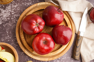 Wooden plate with fresh red apples on dark background