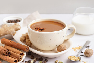 Cup of tasty masala tea with different spices on light background, closeup
