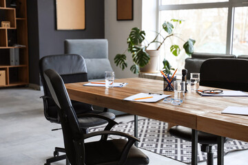 Table with stationery and armchairs prepared for business meeting in modern conference hall