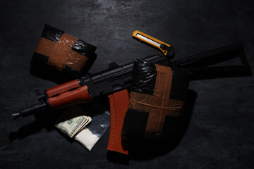 Fototapeta premium Drug packages with gun, money and utility knife on dark background