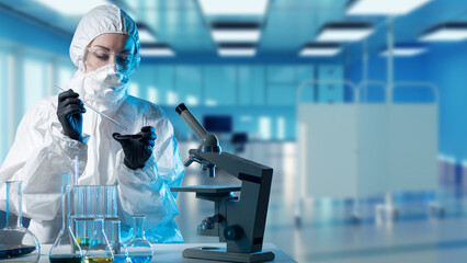 Woman lab technician near microscope. Woman scientist in chemical protection suit. Lab technician...