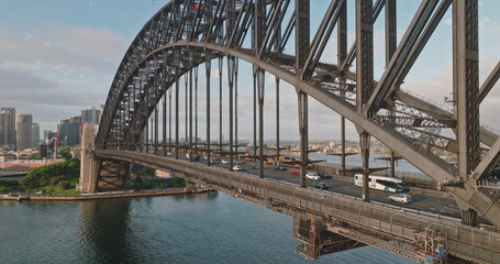 Australia, Sydney: Cars and buses driving Sydney Harbour Bridge during sunny morning rush traffic hour in city center, travel destination, modern city architecture skyline in background. Aerial view