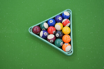 Billiard balls arranged in triangle rack on green felt table