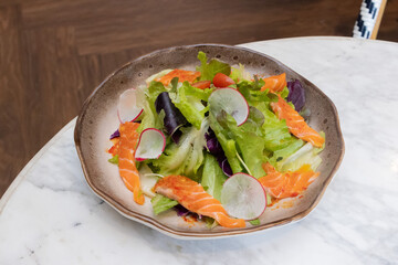 Fresh salad with shrimps and salmon served with vegetables on a plate