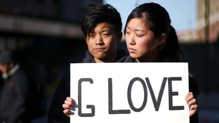 Young couple holding a sign that says 'Love' demonstrating affection and togetherness