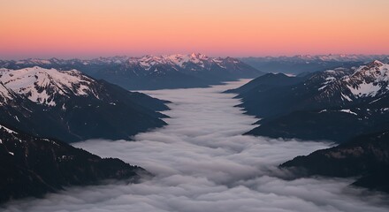 Naklejka premium Dramatic Mountain Valley Filled with Low-Lying Clouds at Sunset, Snow-Capped Peaks and Dense Fog in a Vast Mountainous Landscape at Dawn