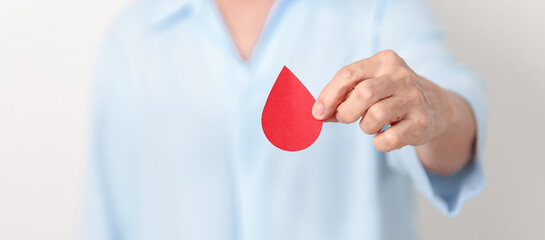 Elderly woman in blue shirt with red Blood drop for World Diabetes Day, Blue November Health month, Diabetes awareness, Blood sugar check, Insulin, Glucose screening, blood donoo and Health checkup