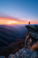 Fototapeta premium Hiker watching colorful sunrise over majestic mountain range from rocky cliff
