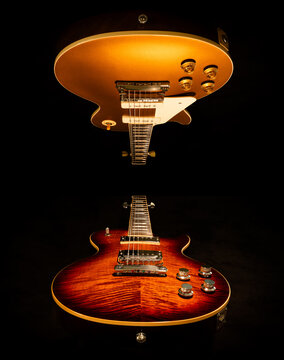 Two electric guitars in a mirrored image.  One a gold top with P90 pickups and one a flame top with humbucker pickups 