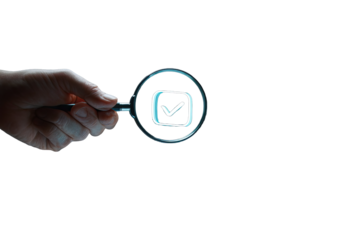 Hand holding magnifying glass focusing on a checkmark icon