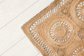 Trendy wicker carpet on white wooden floor in living room, top view