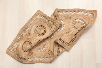 Trendy wicker carpet on white wooden floor in living room, top view