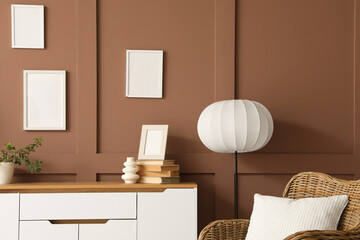 Chest of drawers with houseplant, vase and books near brown wall in living room, closeup
