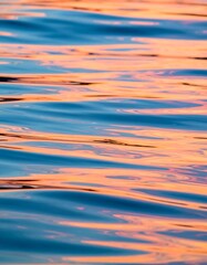 Fototapeta premium Calm water surface reflecting sunset hues, creating an abstract pattern of orange and blue