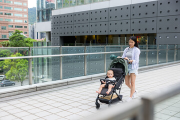 Mother walk with her baby son on pram in city