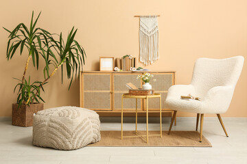 Interior of living room with books on commode, armchair and table