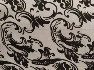 Black ornate floral patterns on a white fabric background, creating an elegant and classic decorative design.