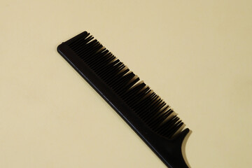 A black comb is placed on a yellow background