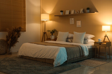 Interior of dark room with bed, tables and glowing lamps at night
