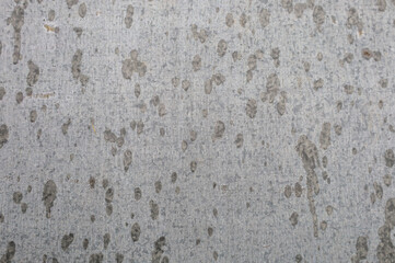 ​A close-up shot shows the texture of old metal covered with dirty spots and traces of droplets. The grey background with rust, scratches, and other defects creates an interesting surface, suitable fo