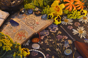 Mystic still life with open magic book of spells, flowers, crystals, black candles and witchy ritual objects.  No foreign language, only fantasy symbols