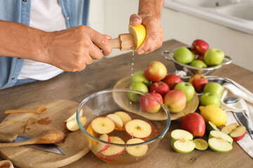Mature man squeezing lemon for apple cider in kitchen, closeup