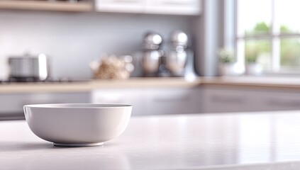A simple white bowl sits on a bright kitchen counter, a blurred modern kitchen is in the background, sunlight streams in from a window