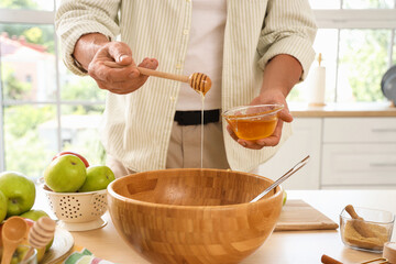 Mature man with honey making apple cider at table in kitchen