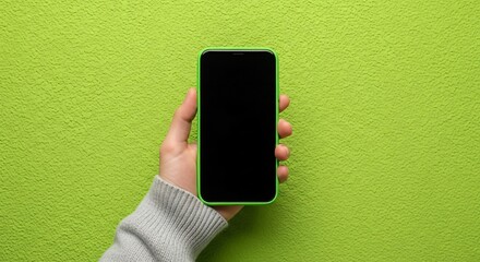 Hand holding modern smartphone with blank screen on textured green background