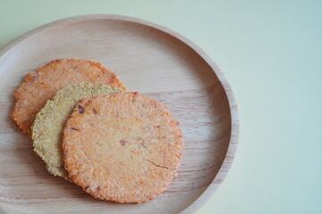 木の皿に並べられた色とりどりの明太子味の煎餅。福岡県土産。