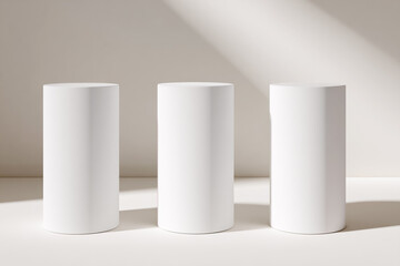 3 white, minimal cylindrical pedestal podiums on a light background,