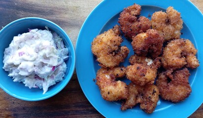 Breaded fried shrimp (prawns) served with creamy coleslaw. Golden crispy coating with soft, juicy insides. Delicious combo of golden fried prawns (shrimp) and tangy coleslaw perfect for seafood lovers