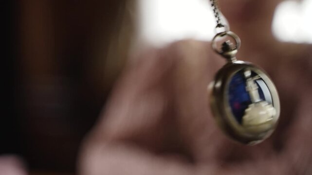 Pendulum in the form of metal medallion on chain swings to the right and left. Hypnosis session