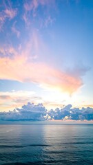 Obraz premium Blurred sunset over calm ocean; pastel colors dominate the sky